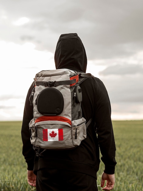 hombre, proceso de llevar, mochila, con, bandera canadiense