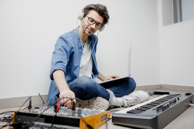 El hombre produce banda sonora electrónica o pista en proyecto en casa