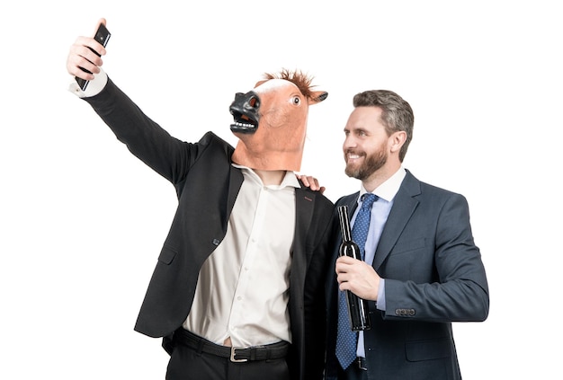 Hombre profesional feliz con máscara de cabeza de caballo y gerente borracho toman autorretrato con teléfono móvil aislado en selfie blanco