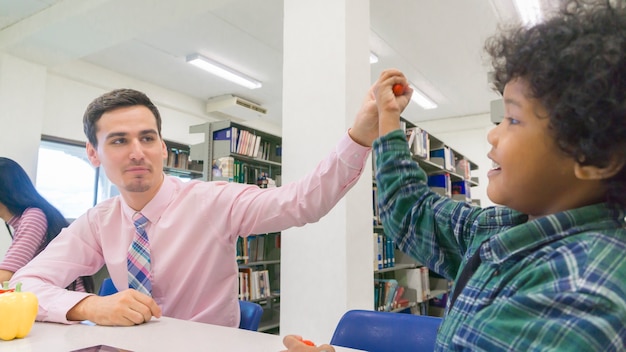 Foto hombre profesor y niño estudiante aprenden con el libro en el fondo del estante