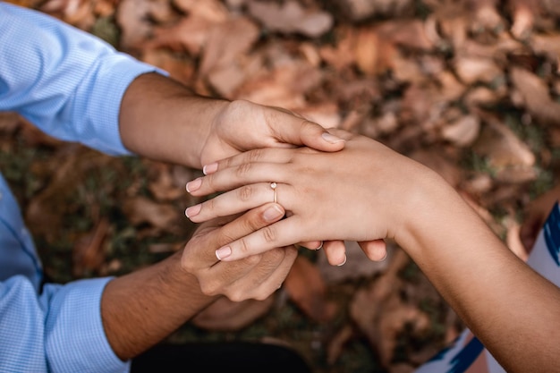 Foto hombre proponiendo matrimonio a una chica y poniendo el anillo de compromiso en su dedo