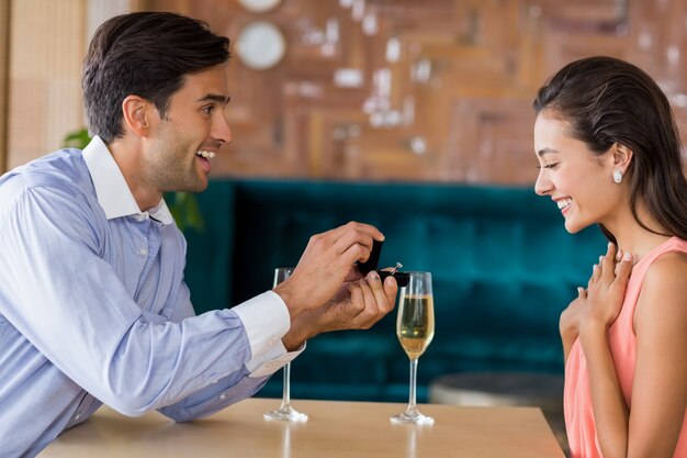 Hombre proponiendo a mujer ofreciendo anillo de compromiso