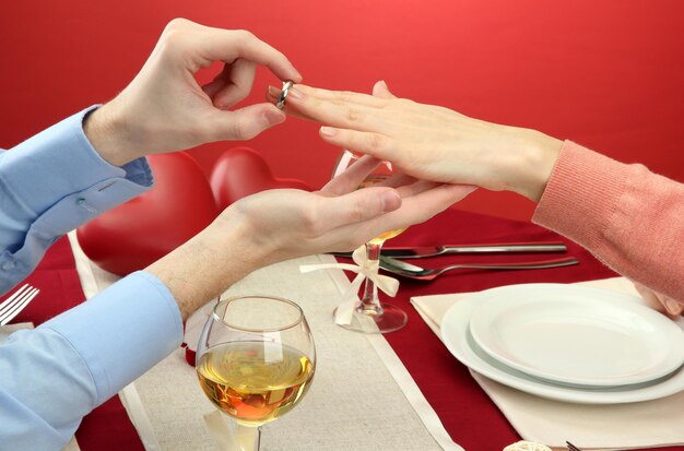 Un hombre proponiendo y sosteniendo un anillo de compromiso sobre la mesa del restaurante