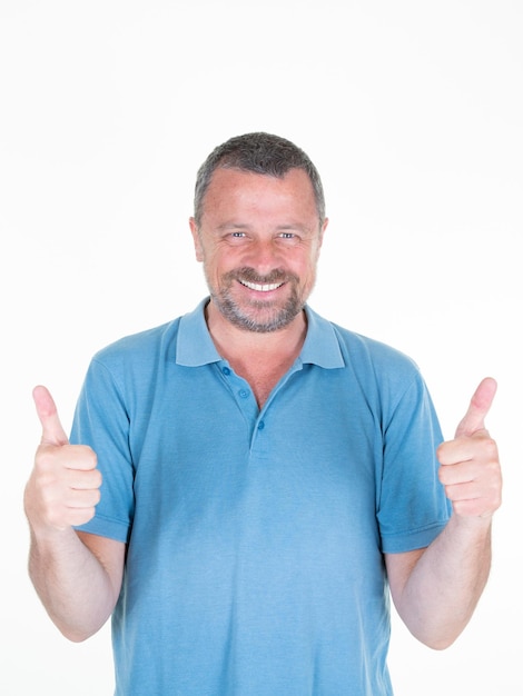 Foto hombre con el pulgar hacia arriba guapo de mediana edad sonriendo feliz en camisa azul sobre fondo blanco.