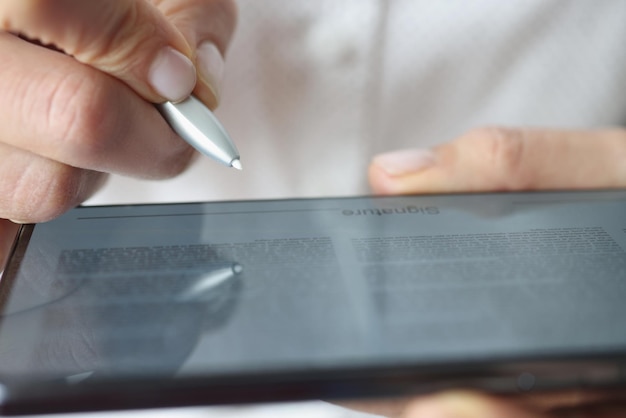El hombre puso la firma en el documento abierto del dispositivo de tableta digital y el espacio para firmar