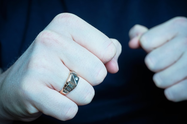 El hombre puso puños amenazantes con un anillo. Azul tonificado.