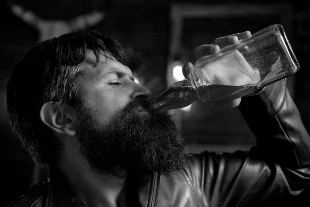 El hombre que bebe está revisando su teléfono hombre sosteniendo un vaso de whisky bebiendo una degustación de whisky