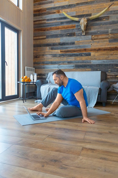 Hombre que busca rutinas de ejercicio en línea en casa entrenamiento en línea foto vertical