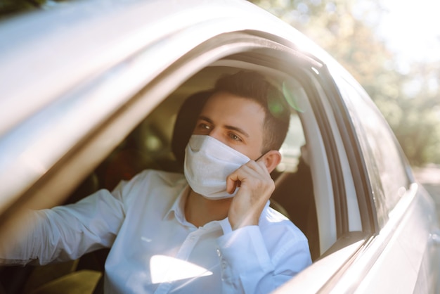 Un hombre que conducía un automóvil se pone una máscara médica durante una epidemia en una ciudad en cuarentena.