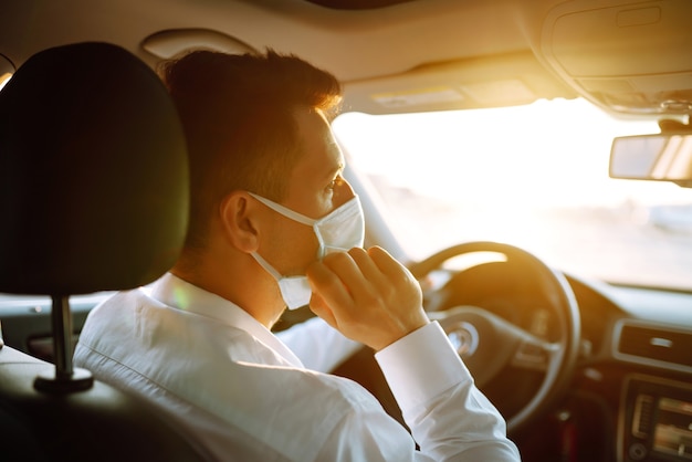 Un hombre que conducía un automóvil se pone una máscara médica durante una epidemia en una ciudad en cuarentena.