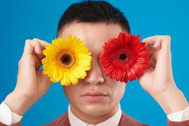 Hombre que cubre los ojos con flores