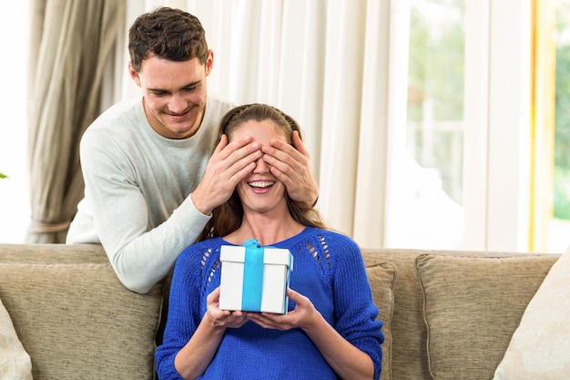 Hombre que cubre los ojos de la mujer mientras le da un regalo sorpresa.