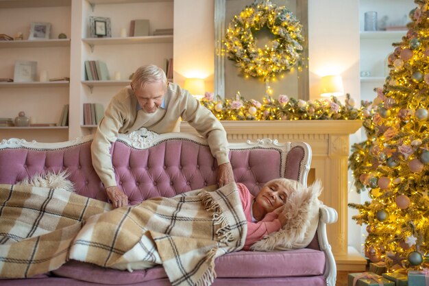 hombre que cubre a su esposa durmiendo con un plaid