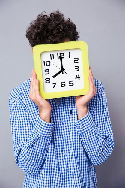 Hombre que cubre su rostro con gran reloj