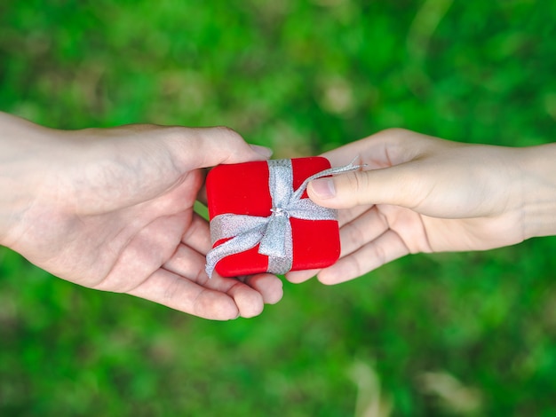 Hombre que da un rectángulo de regalo rojo a la mujer.