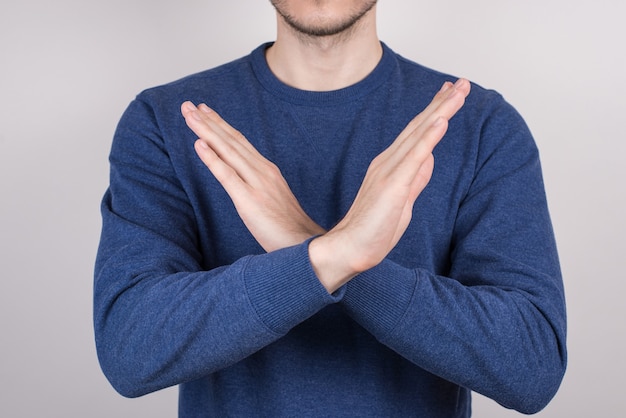 Hombre que demuestra dos manos cruzadas aislado fondo gris