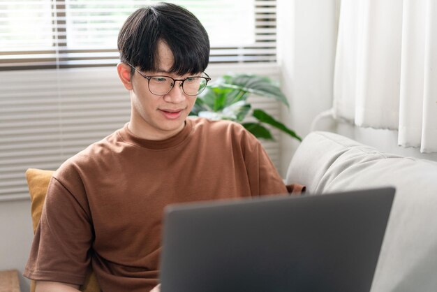 hombre que se está poniendo anteojos mientras se enfoca en la pantalla de la computadora portátil