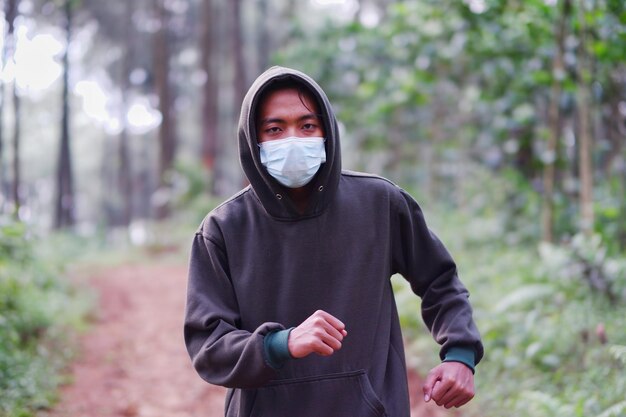 Un hombre que está trotando en el bosque, al cumplir con el protocolo de salud COVID-19, usa una máscara.