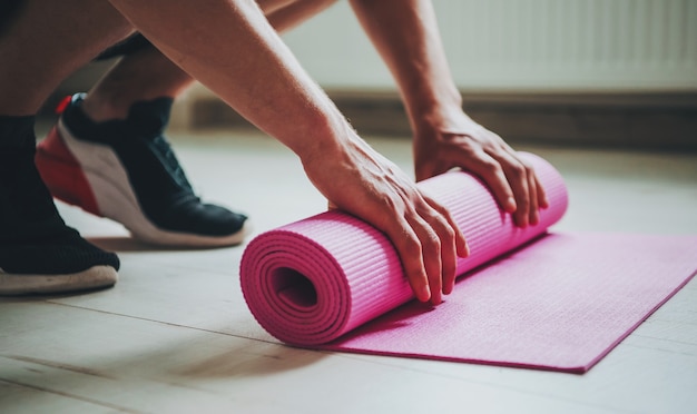 El hombre por el que se establecen su estera de yoga preparándose para un complejo de ejercicios matutinos para el cuidado del cuerpo