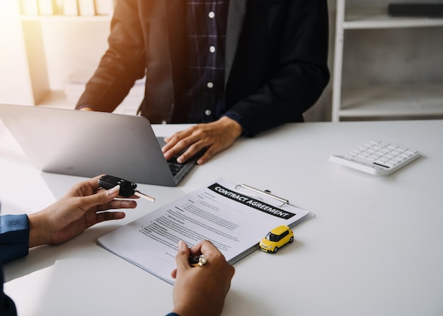 Hombre que firma el documento del seguro del automóvil o el documento de arrendamiento Escribir la firma en el contrato o acuerdo Compra o venta de vehículos nuevos o usados Llaves del automóvil en la mesa Garantía o garantía Cliente o vendedor