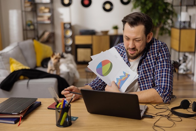 Un hombre que habla con una camiseta blanca muestra documentos hacia una computadora portátil