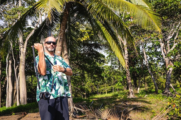 Hombre que lleva una cámara digital en un ambiente tropical