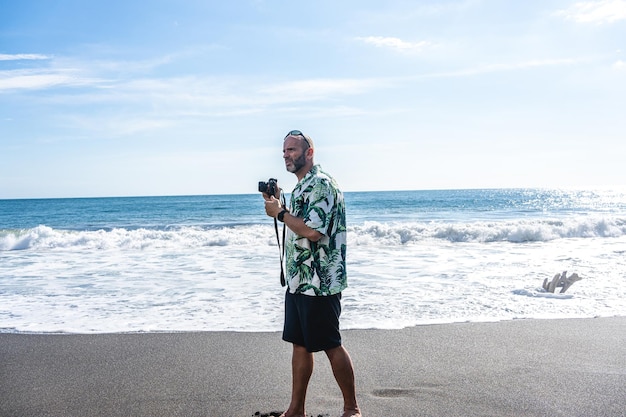 Hombre que lleva una cámara digital en una playa tropical