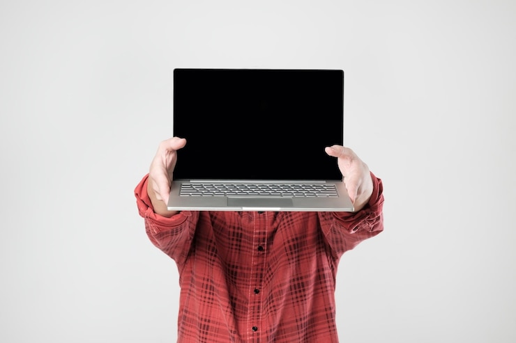 Foto hombre que lleva una computadora portátil y muestra la pantalla de pie ocultando su rostro