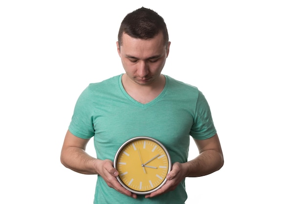 Hombre que llevaba una camiseta verde y sostiene un reloj sobre fondo blanco aislado