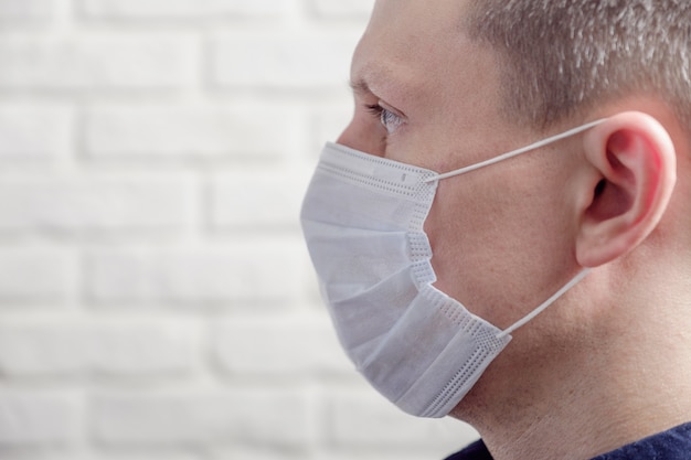 Foto hombre que llevaba una máscara médica contra la pared
