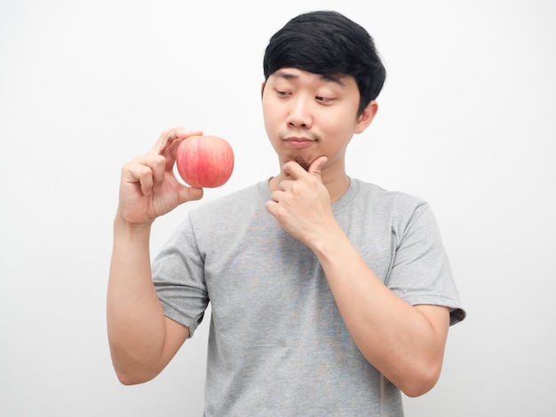 Hombre que mira la manzana roja en su mano que piensa en el fondo blanco de la atención sanitaria