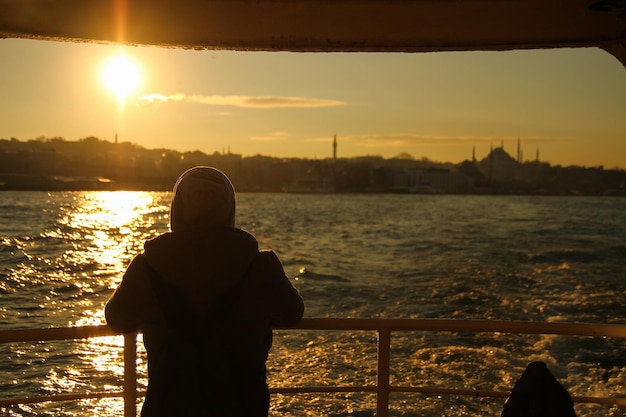 El hombre que mira la puesta de sol en Estambul desde detrás del ferry