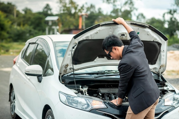 Un hombre que mira la sala de máquinas de su automóvil parece tener un concepto de condición anormal sobre el seguro del automóvil