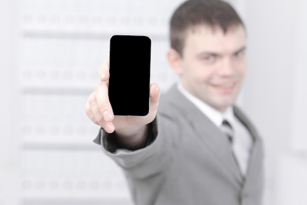 Hombre que muestra la pantalla del teléfono inteligente mientras está parado en la oficina