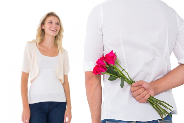 Hombre que oculta el ramo de rosas de mujer