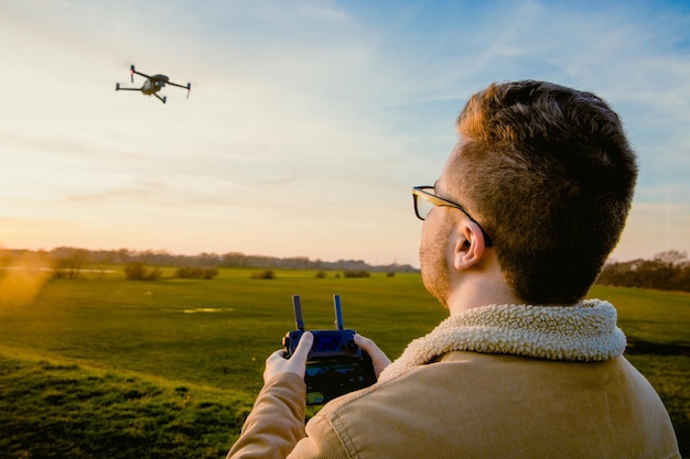 Hombre que opera un dron con control remoto mientras está de pie en el campo