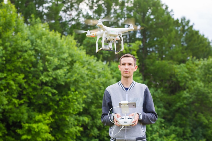 Foto hombre que opera drones volando o flotando por control remoto en la naturaleza