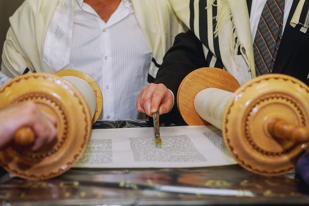 Un hombre que ora con un tefilín en el brazo y la cabeza, sosteniendo una Torá, mientras lee una oración.