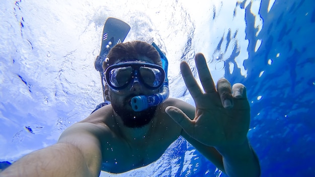 Un hombre que practica snorkel no está en el mar rojo y muestra diferentes gestos con las manos.