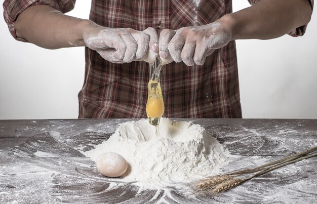 Hombre que prepara la masa de pan en la tabla de madera en un cierre de la panadería para arriba