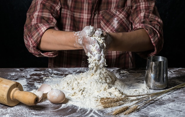 Hombre que prepara la masa de pan en la tabla de madera en un cierre de la panadería para arriba