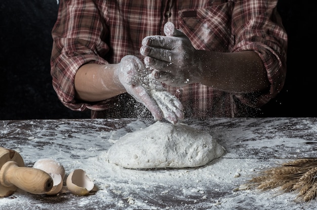 Hombre que prepara la masa de pan en la tabla de madera en un cierre de la panadería para arriba