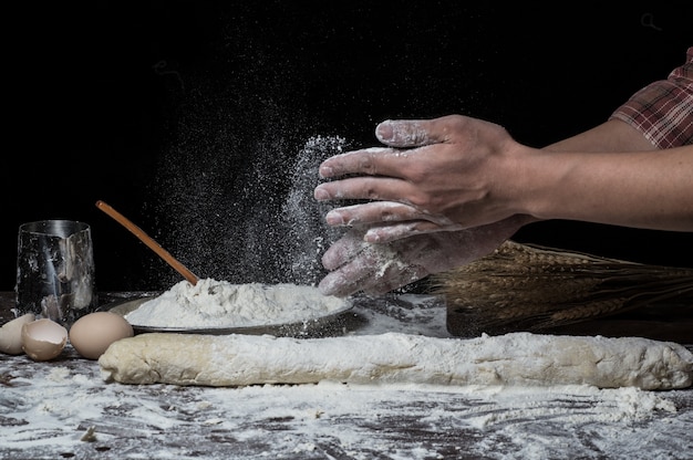 Hombre que prepara la masa de pan en la tabla de madera en un cierre de la panadería para arriba