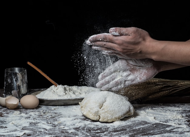 Hombre que prepara la masa de pan en la tabla de madera en un cierre de la panadería para arriba