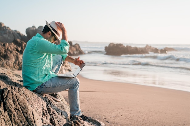 hombre que sienta, con, un, computador portatil, solo, en la playa