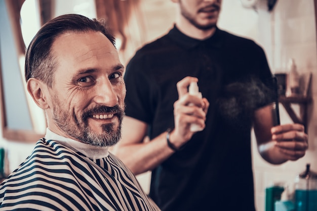 Hombre que se sienta en silla en cortes en barbería