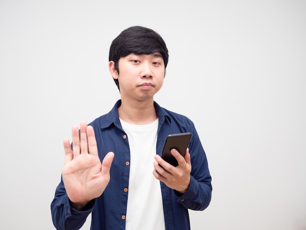 Hombre que se siente aburrido y que sostiene el teléfono móvil muestra la mano parada blanca aislada