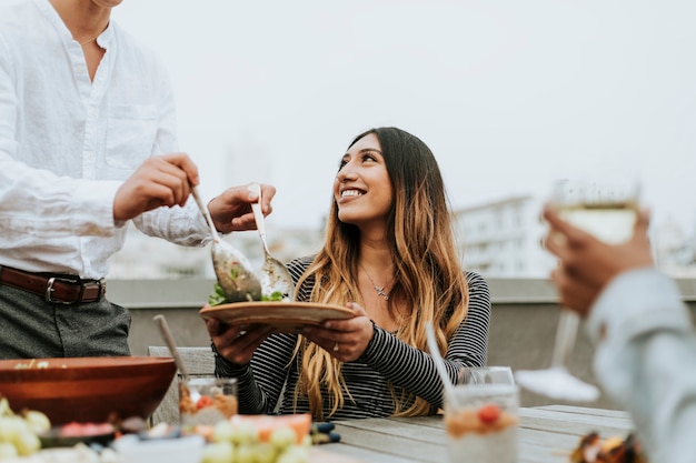 Hombre que sirve su ensalada de amigos en una fiesta en la azotea