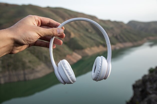 Hombre que sostiene los auriculares en la superficie de la montaña. concepto de sonido de la naturaleza