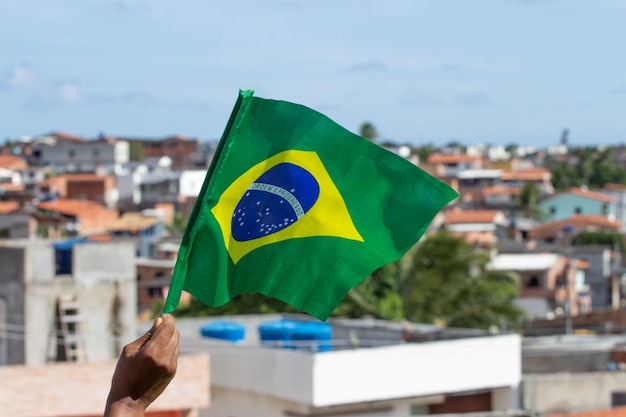 Hombre que sostiene una bandera brasileña frente a la comunidad